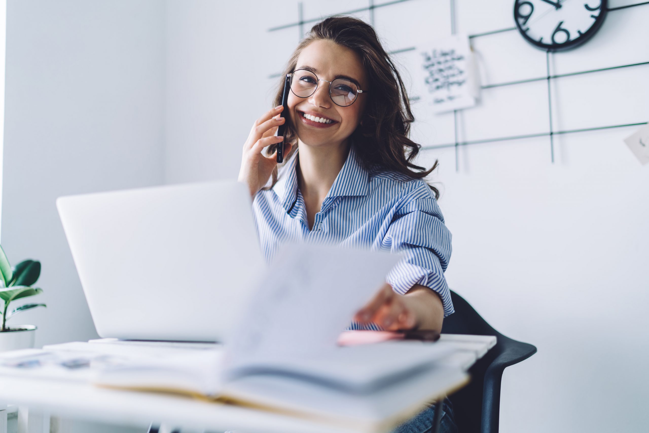 Young woman laughing while talking on cellphone in office